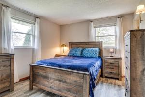 a bedroom with a bed with blue sheets and two windows at Quaint Economy Retreat with Patio and Spacious Yard! 