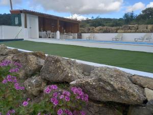 een steunmuur met paarse bloemen voor een huis bij Casinha de férias no campo - Quintinha dos Cavalos - Arruda dos Vinhos in Sabugos