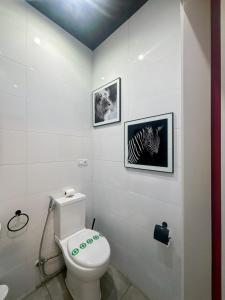a bathroom with a toilet and two pictures on the wall at Utopía Alicante - Adults Experience in Alicante