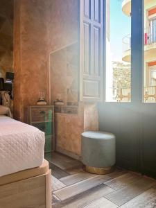 1 dormitorio con cama, ventana y taburete en Utopía Alicante - Adults Experience, en Alicante