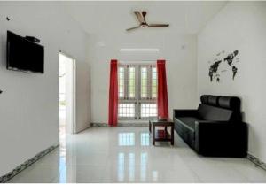 sala de estar con sofá negro y cortinas rojas en Stay in serinity beach 2bhk villa., en Pondicherry