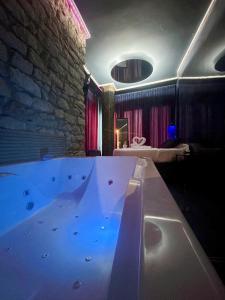 Habitación con bañera grande y pared de piedra. en Utopía Alicante - Adults Experience, en Alicante
