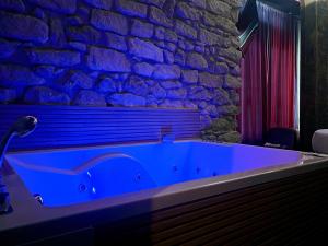 bañera azul en una habitación con pared de piedra en Utopía Alicante - Adults Experience en Alicante