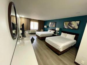 Habitación de hotel con 2 camas y TV en Portside Inn & suites, en San Pedro