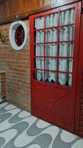 una puerta roja con una ventana en una pared de ladrillo en Casinha Aconchegante no 3° Melhor Clima do Mundo., en Miguel Pereira