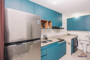 a kitchen with blue cabinets and a stainless steel refrigerator at Nosso Apê Teixeiras: 2/4 | Garagem | Acessível NA812T in Juiz de Fora