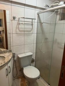 a bathroom with a toilet and a glass shower at Apartamento Mobiliado com Área de Lazer in Caldas Novas
