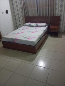 a bed sitting in a room with a tiled floor at Crale and Busino in Port Harcourt