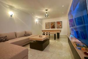 a living room with a couch and a table and a tv at Grand Appartement Agdal Centre I Suite & Billard in Rabat