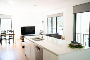 a kitchen and living room with white cabinets and a couch at Spacious & Modern 4 Bedrooms in Tuggeranong