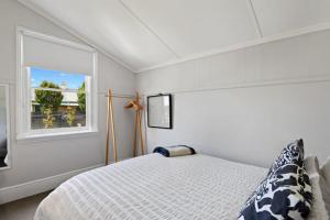 een witte slaapkamer met een bed en een raam bij North Hobart cottage in Hobart
