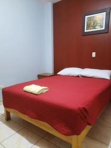a bed with a red blanket and white pillows on it at Isabel's INN - Nasca in Nazca