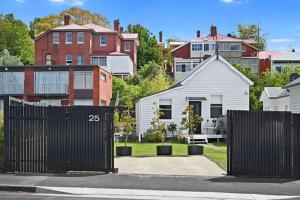 una cerca negra frente a un patio con casas en North Hobart cottage, en Hobart