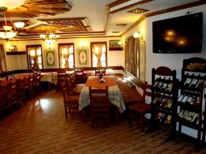 a dining room with tables and chairs and a television at Voevodski Eco Complex in Katunishte