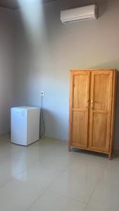 Elle comprend un réfrigérateur blanc et une armoire en bois. dans l'établissement MEDPY HOSTEL, à Pedro Juan Caballero