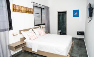 1 dormitorio con 1 cama con sábanas blancas y almohadas rosas en Hotelito Bonito Eli & Edw en Santo Domingo