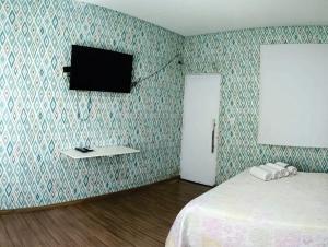 a bedroom with a bed and a tv on a wall at OLÍMPIA APARTS Kitnet com cozinha e banheiro privativo PISCINA AQUECIDA in Olímpia