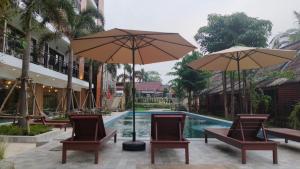 a pool with chairs and umbrellas in front of a resort at Vang Vieng Bungalows in Vang Vieng
