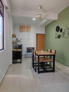 a dining room with a table and chairs and a kitchen at Suite Us Guesthouse Kubang Kerian in Kota Bharu