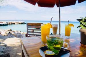 a table with two glasses of orange juice on it at NEW Amazing Villa with Sea Views-Walk to Beach-8 guests-Private Pool in Willibrordus