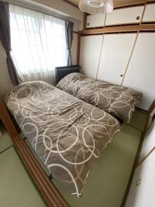 Bett in einem kleinen Zimmer mit Fenster in der Unterkunft Ueda Building - Vacation STAY 8560 in Asahikawa