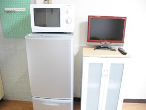 eine Mikrowelle und ein Computer auf dem Kühlschrank in der Unterkunft Ueda Building - Vacation STAY 8560 in Asahikawa