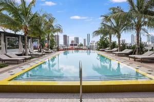 a swimming pool with chairs and palm trees on a building at Wynwood Luxury & Modern Apt in Miami