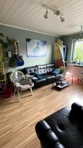 sala de estar con sofá de cuero negro y guitarras en Great cozy city apartment self check in, en Hannover