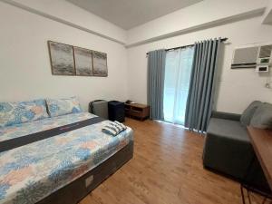 a bedroom with a bed and a chair and a window at ANIA CONDO STAY in Mactan