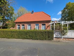 ein Backsteinhaus mit einem orangenen Dach und einem weißen Zaun in der Unterkunft Dat Fischerhus - Horumersiel in Wangerland