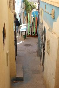an alley way with surfboards on the side of a building at Taghazout Flats in Taghazout