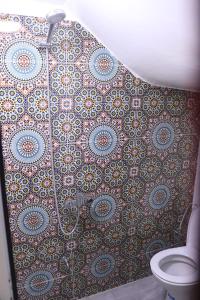 a bathroom with a tile wall and a toilet at Taghazout Flats in Taghazout +24 photos