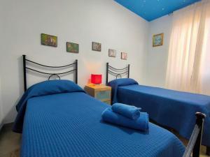 2 bedden in een slaapkamer met blauwe lakens bij Casa a Matrice a Barrafranca in Barrafranca