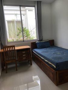 een slaapkamer met een bed, een bureau en een raam bij The Greenery in Phnom Penh