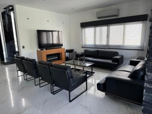 a living room with black furniture and a tv at Casa en el CID DE MAZATLÁN, SINALOA in Mazatlán
