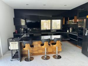 a kitchen with black counters and bar stools at Casa en el CID DE MAZATLÁN, SINALOA in Mazatlán