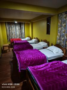 uma fila de camas num quarto com capas roxas em Kharga Homestay em Darjeeling