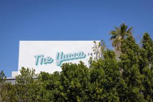 un cartel que dice theuminati en un edificio con árboles en The Yucca Hotel Villa - Entire Buyout, en Desert Hot Springs