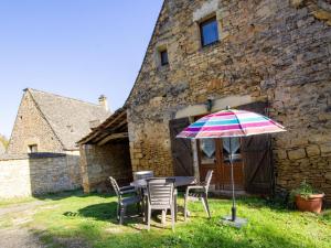tavolo e sedie con ombrellone di fronte a un edificio di Charmante maison périgourdine avec jardin, cheminée, Wifi et équipements bébé, proche de Sarlat - FR-1-616-130 a Saint-André-dʼAllas
