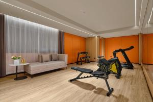 een woonkamer met een bank en een fitnessruimte bij Pearl Hotel - Gongbei Port Zhuhai in Zhuhai