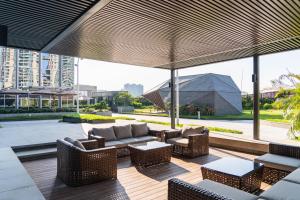 un patio con sillas de mimbre, mesas y ventanas en Sha Zhi Ye Serviced Apartment Hotel - Houjie Wanda Plaza Liaoxia Subway Station, en Dongguan