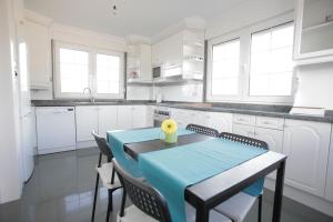 a white kitchen with a blue table and chairs at Gijon Surf Hostel in Gijón