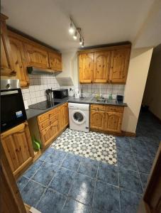 uma cozinha com armários de madeira e uma máquina de lavar roupa em NKY CRYSTAL 4 Bed House Apartment em Londres