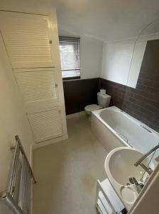 La salle de bains est pourvue d'une baignoire, de toilettes et d'un lavabo. dans l'établissement NKY CRYSTAL 4 Bed House Apartment, à Londres