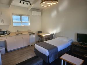 a bedroom with a bed and a kitchen with a sink at Ferrylink Motel in Picton