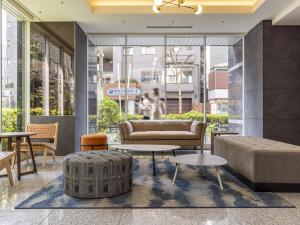 eine Lobby mit einem Sofa, Tischen und Fenstern in der Unterkunft Tokyu Stay Nishi Shinjuku in Tokio