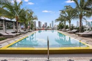 a swimming pool with chairs and palm trees on a building at Wynwood Luxury Penthouse in Miami