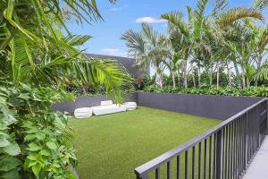 a garden with grass and palm trees and a fence at Wynwood Luxury Penthouse in Miami