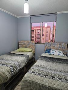 two beds in a room with a window at Departamento Puertas del Mar in La Serena