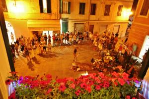 Une foule de gens dans une cour avec des fleurs rouges dans l'établissement R&B Sterlizia, à Finale Ligure